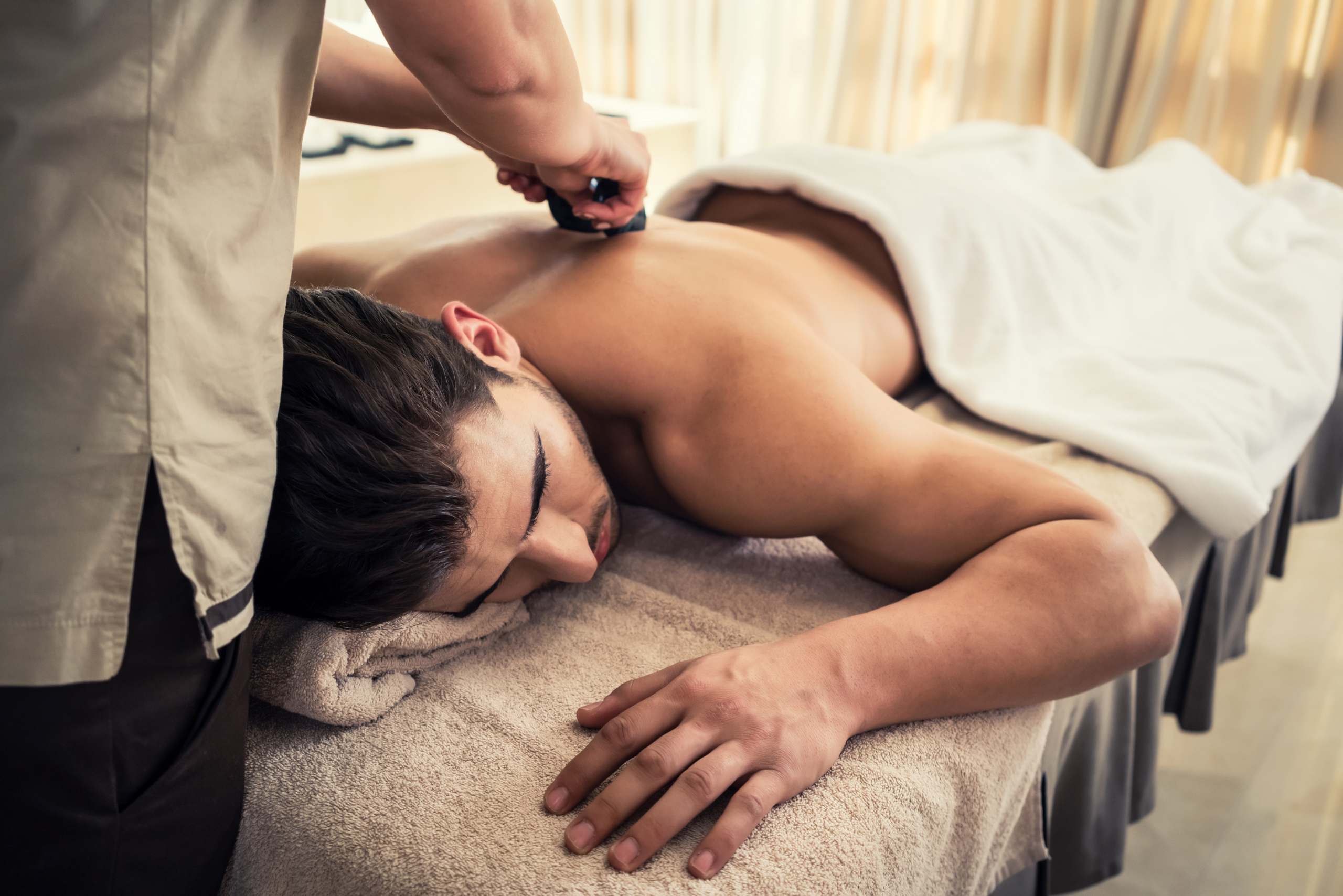 Young man relaxing during traditional massage with hot stones Thaimassage