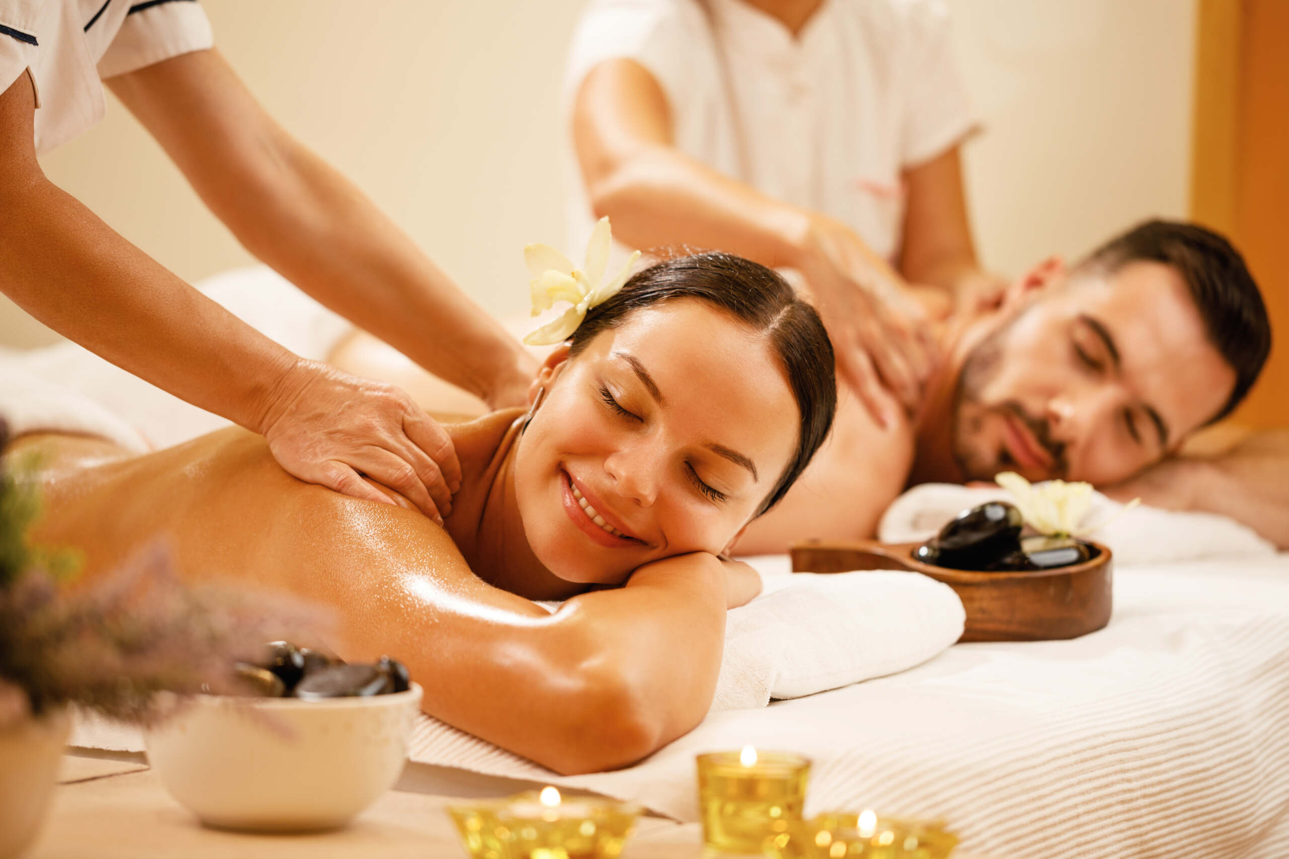 Happy couple enjoying a day at spa while having back massage. Pärchenmassage
